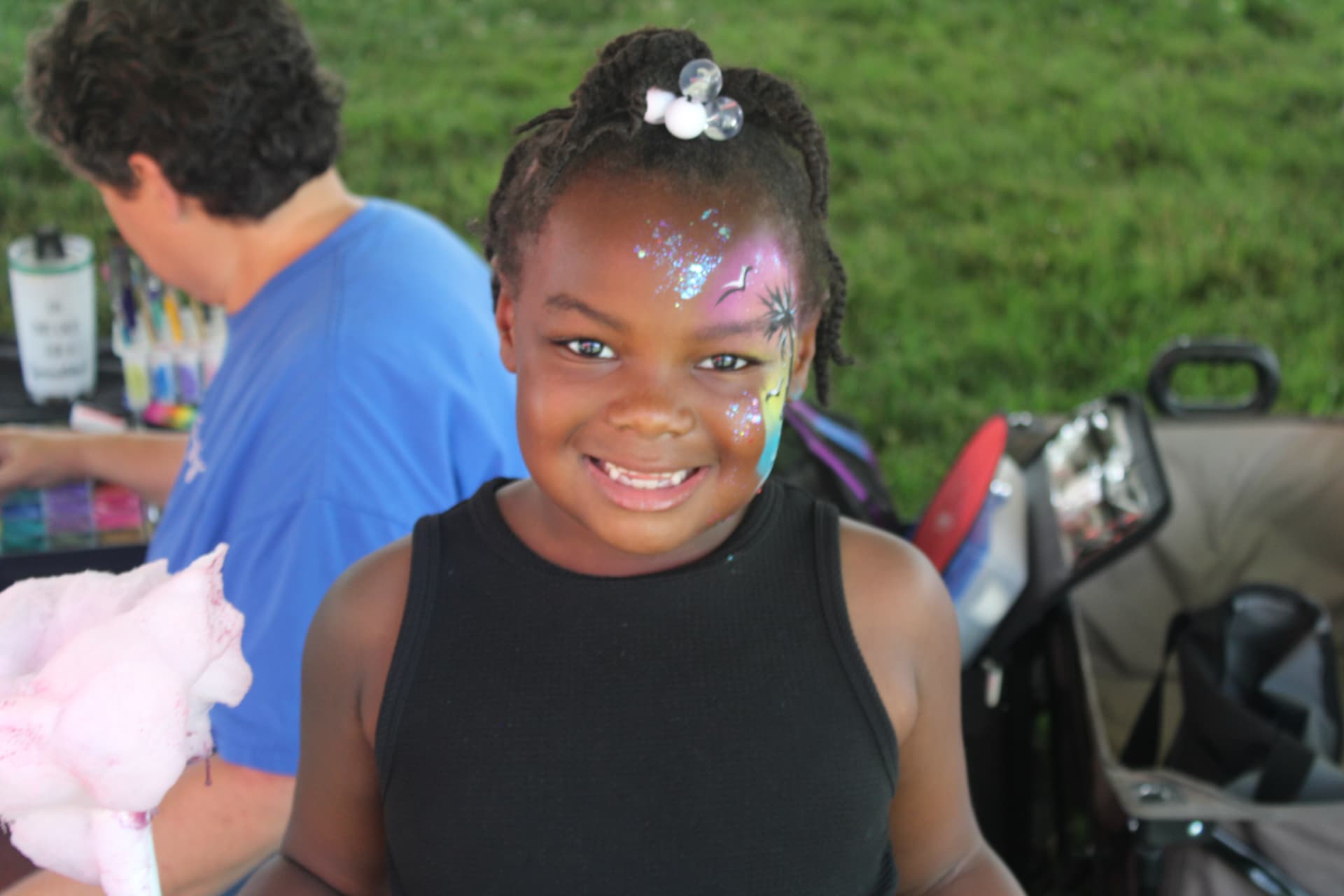 Smiling child with colorful face paint at a community event